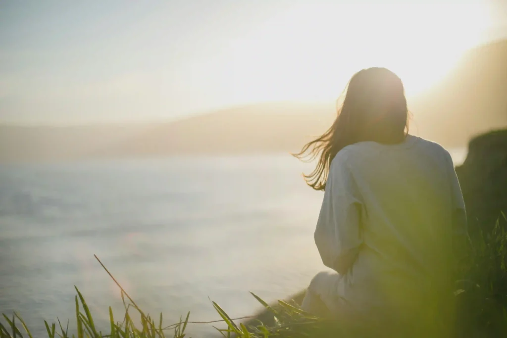 Woman sitting by the ocean, reflecting and resting